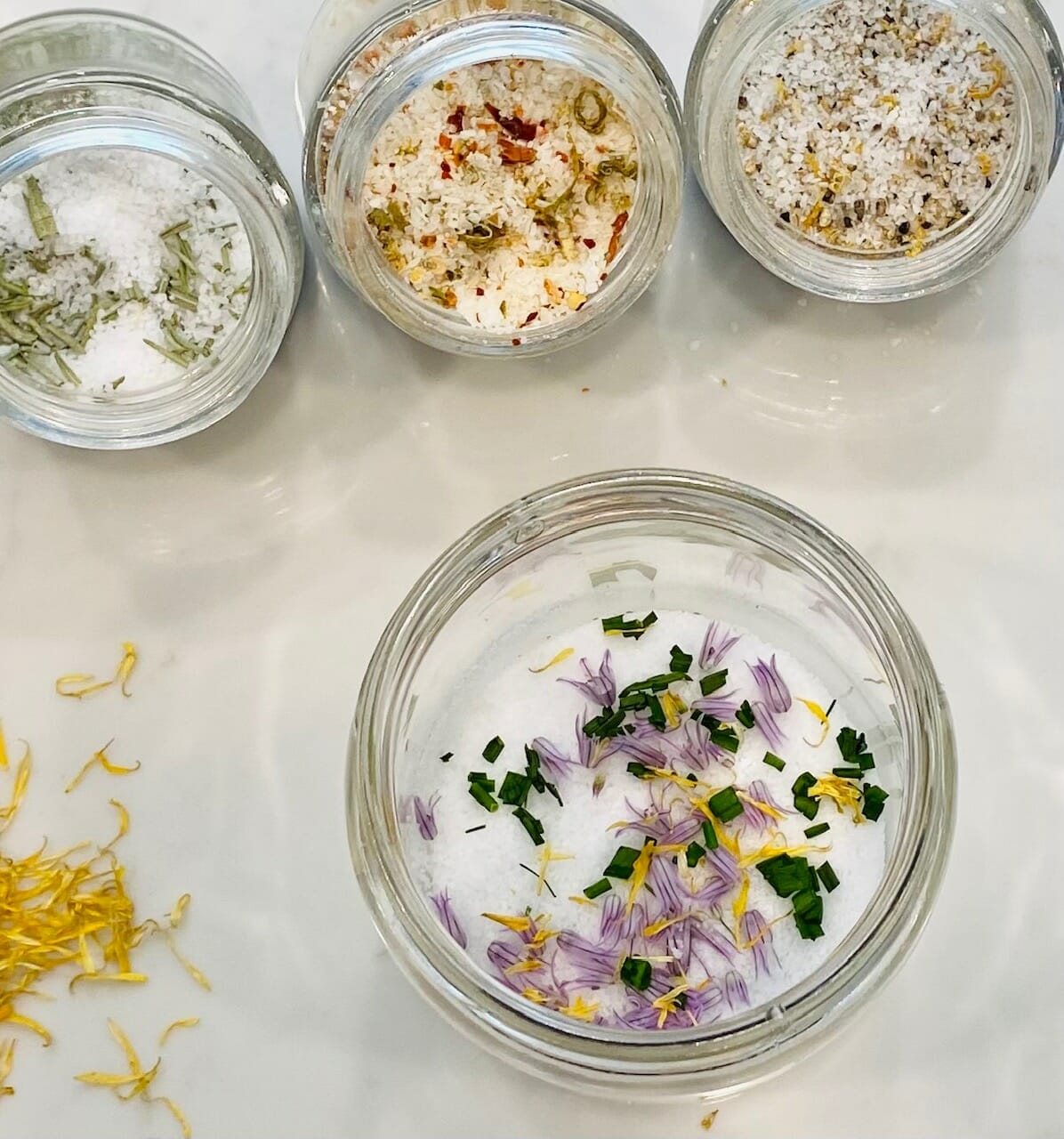 Image of how to make finishing salt: jars open, herbs being added to fresh salt.