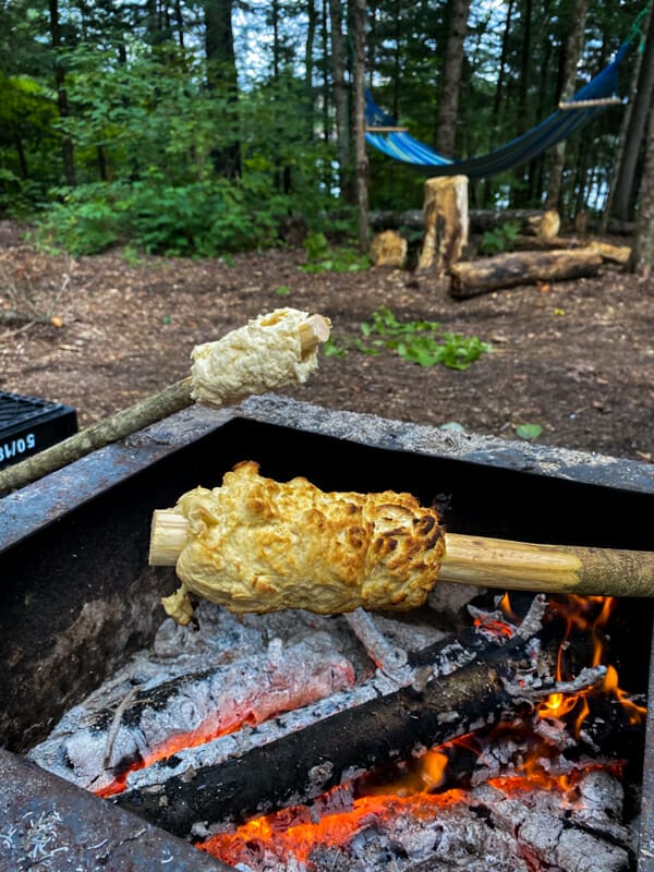 two sticks with bannock over campfire coals