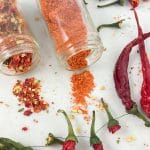 homemade cayenne pepper and pepper flakes jars spilling on table