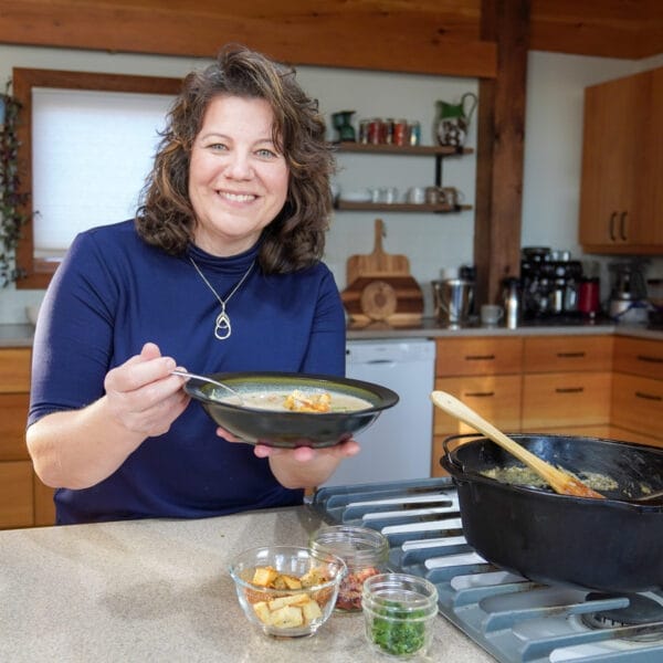 getty holding bowl of soup with optional garnishes in front of her on counter