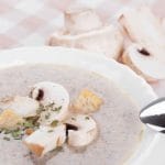 bowl of soup with spoon and whole mushrooms