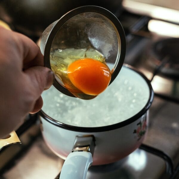 gently sliding egg into boiling water.