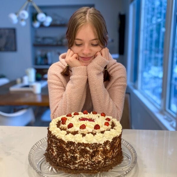 girl sitting and looking at black forest cake