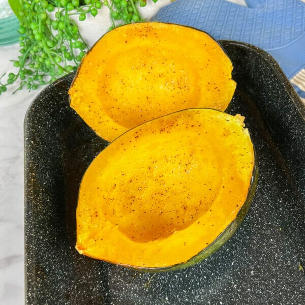 two halves of roasted acorn squash in baking pan