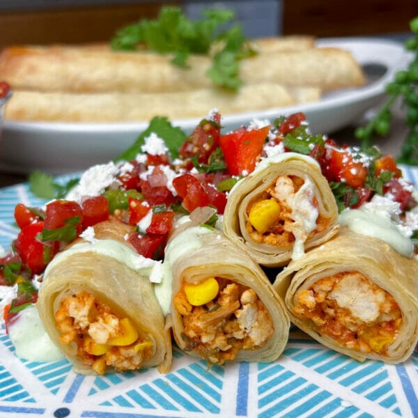 chicken taquitos on plate topped with fresh salsa