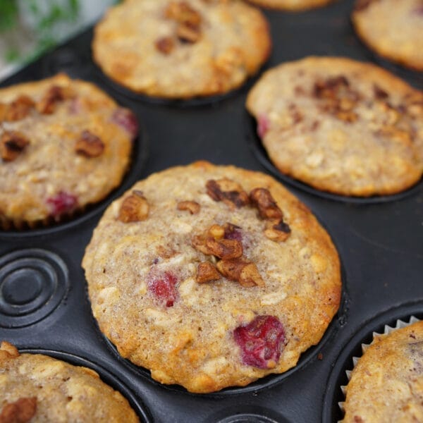 cranberry nut muffins in baking pan with nuts on top