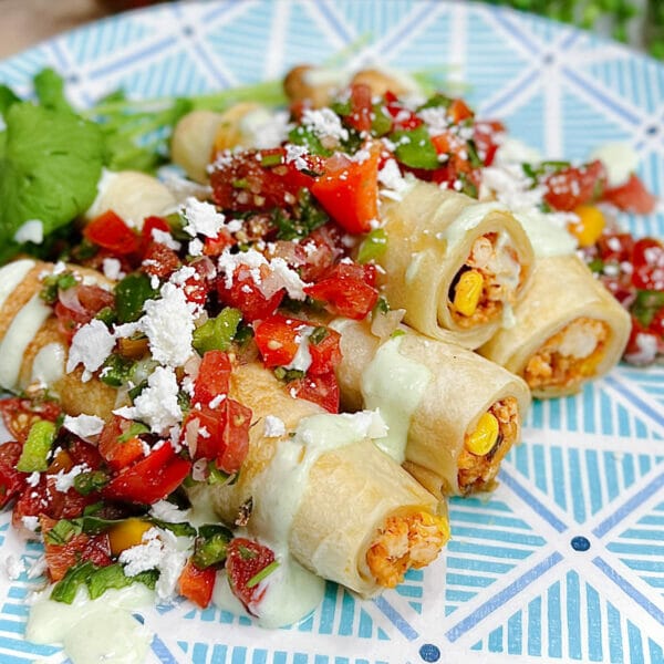 taquitos on plate loaded with fresh salsa and feta