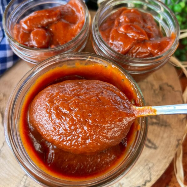 three jars of smooth rhubarb barbecue sauce one with spoon in it