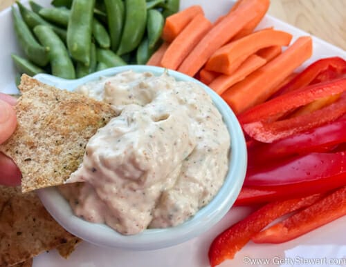 Homemade onion soup mix dip with chip dipped and fresh veggies on the side.