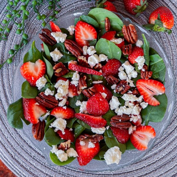 spinach, strawberries, goat cheese and pecans on plate not dressed