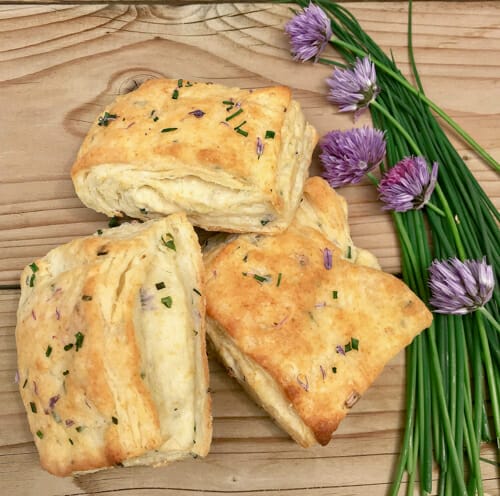three chive biscuits on board with blossoms
