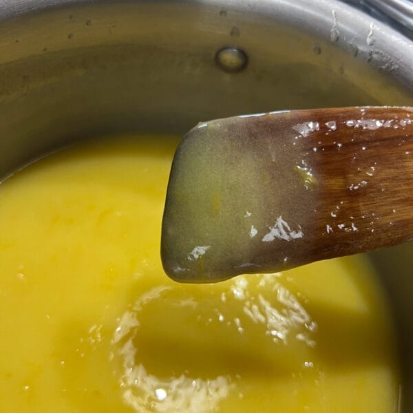 lemon curd sticking to back of wooden spoon over pot
