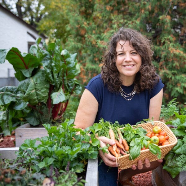 getty holding freshly harvested veggies by garden boxes