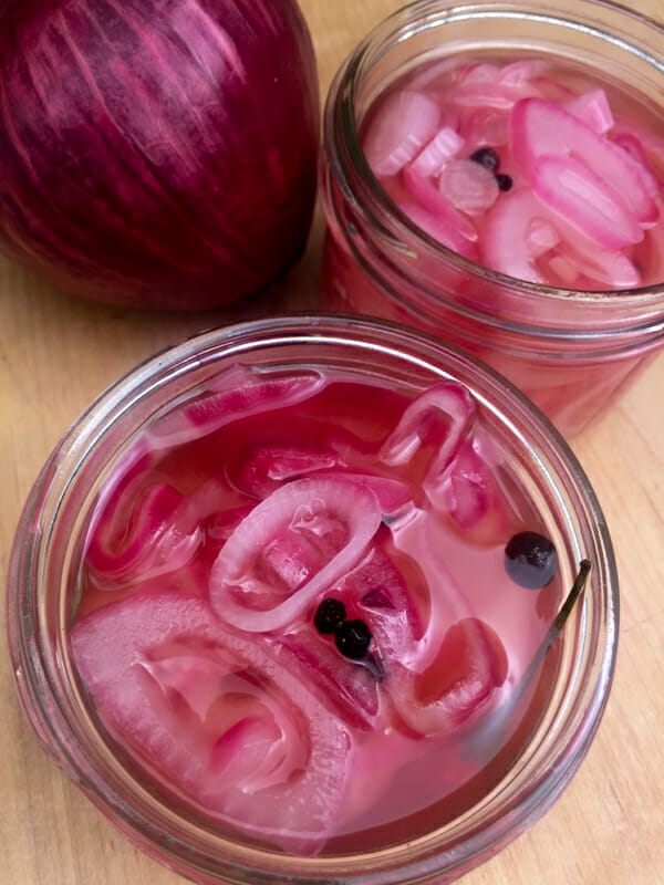 close up of pickled red onions with spices in a jar, no lid