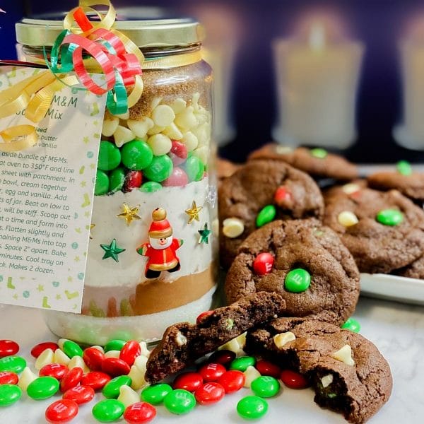 Jar of cookie mix with gift/instruction tags and ribbon. Prepared cookies and m&ms arranged on the side.