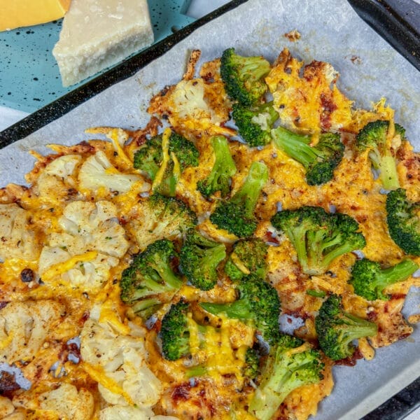 broccoli and cauliflower on baking sheet with crispy cheese baked on