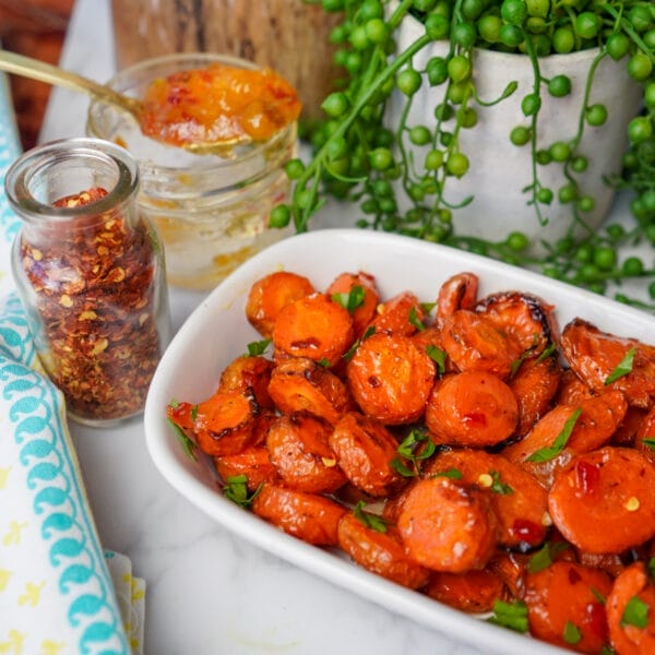 roasted carrot coins with parsley on white serving plate