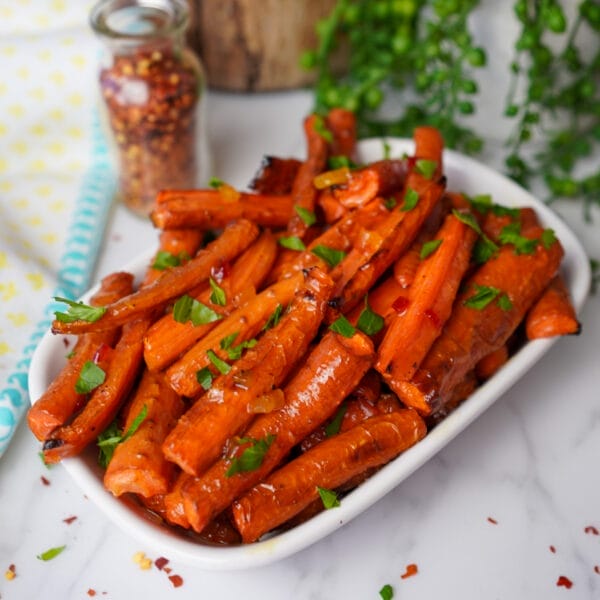 roasted carrot spears with parsley on white serving plate