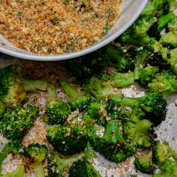 oven roasted broccoli with a bowl of herbed breadcrumbs in corner