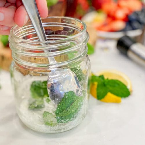 muddling mint and sugar with back of spoon in jar