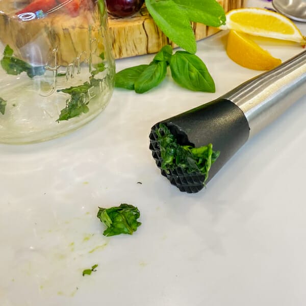 torn basil leaves with green smudges on counter
