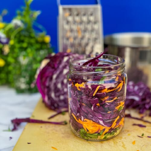 pickled red cabbage in a jar with grater and ingredients in the background