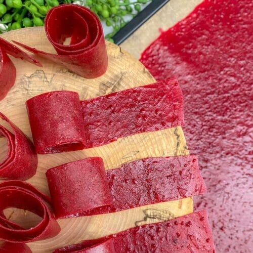 Cranberry fruit rolls curled on cutting board.