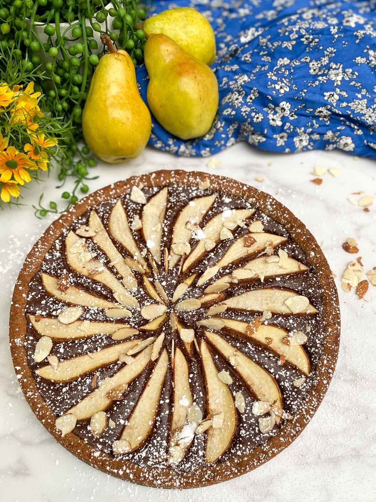 chocolate pear tart decorated with powdered sugar and almond slices