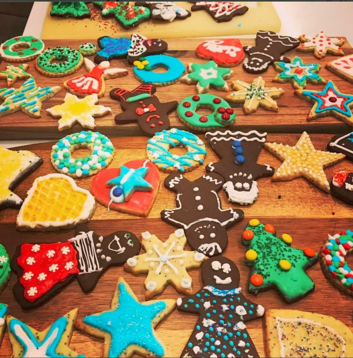 Colourful assortment of decorated holiday cookies spread out on wooden countertop.