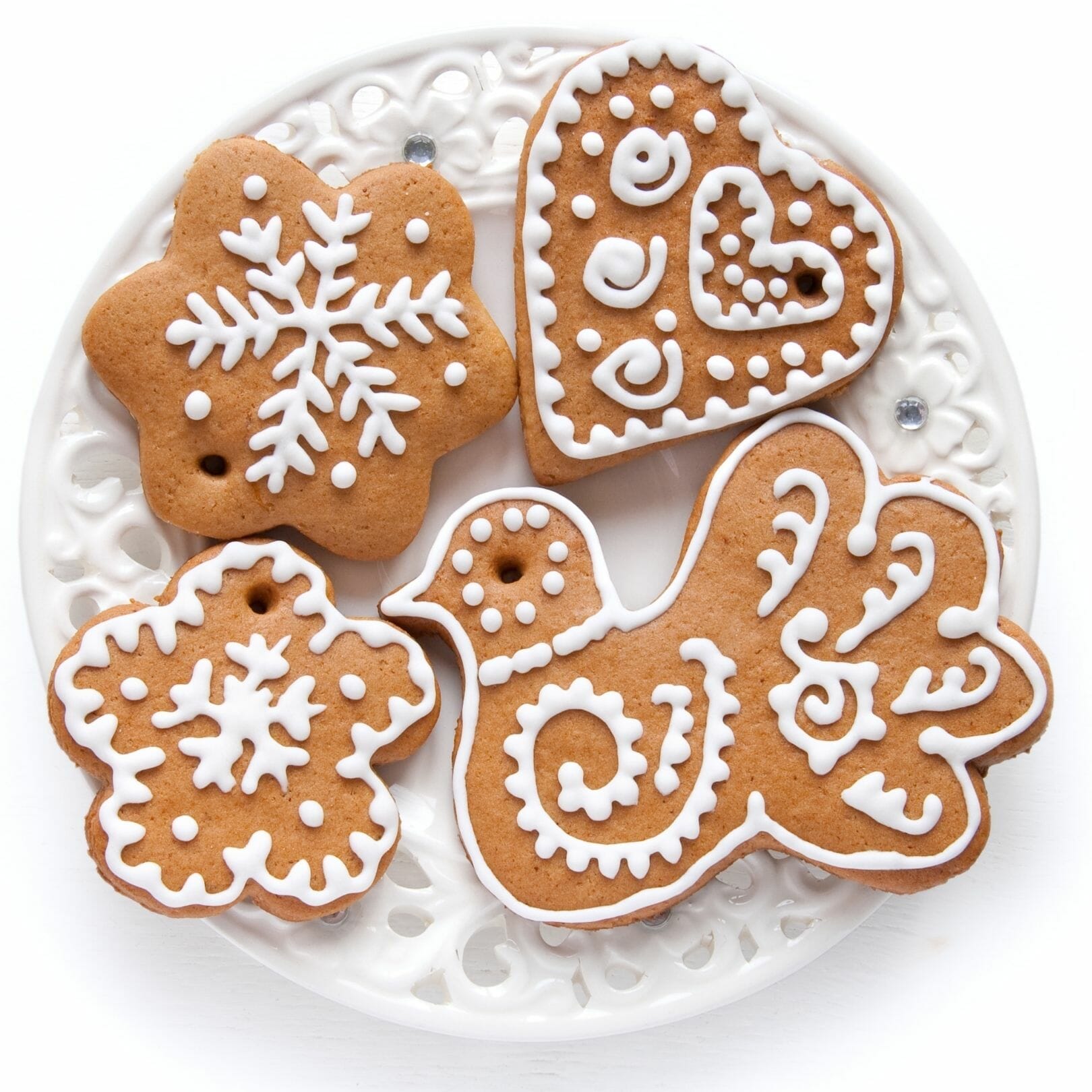 White icing and pretty festive designs on gingerbread cookies. Arranged on a round white plate.