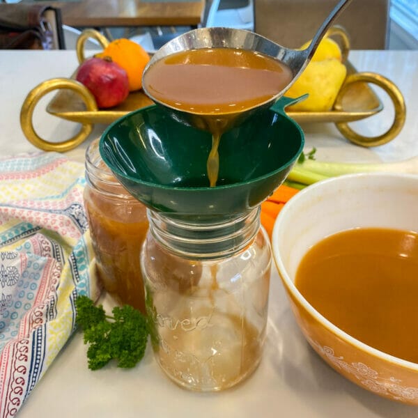 pouring veggie soup broth into jars