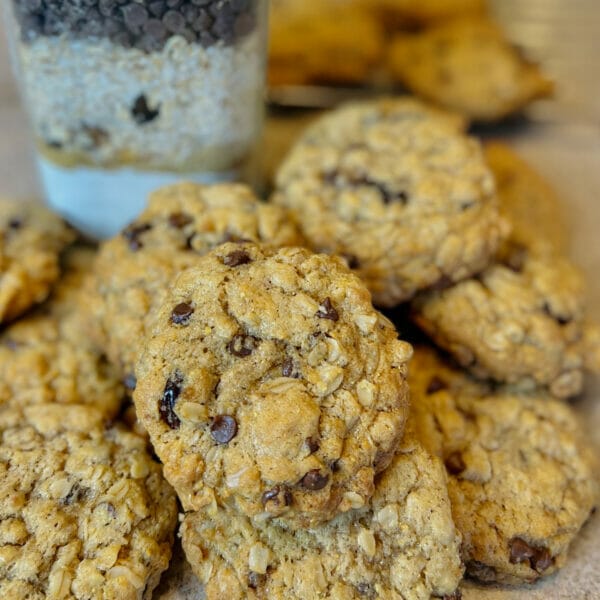 Close up of prepared chocolate chip oat cookie, dry ingredients in the background.
