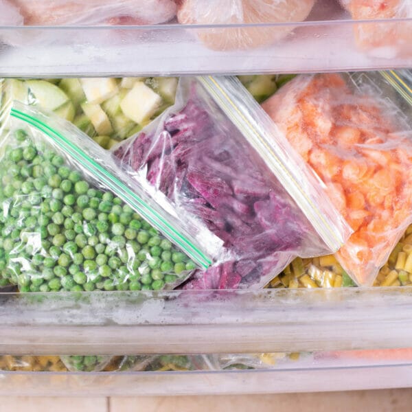 colourful image including bags of frozen peas, beets, carrots, yellow beans and squash in zip bags in a freezer drawer