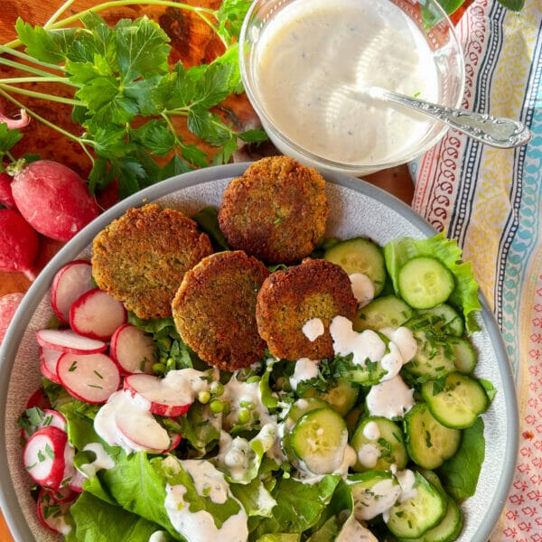 dressed salad in bowl with extra dressing on side