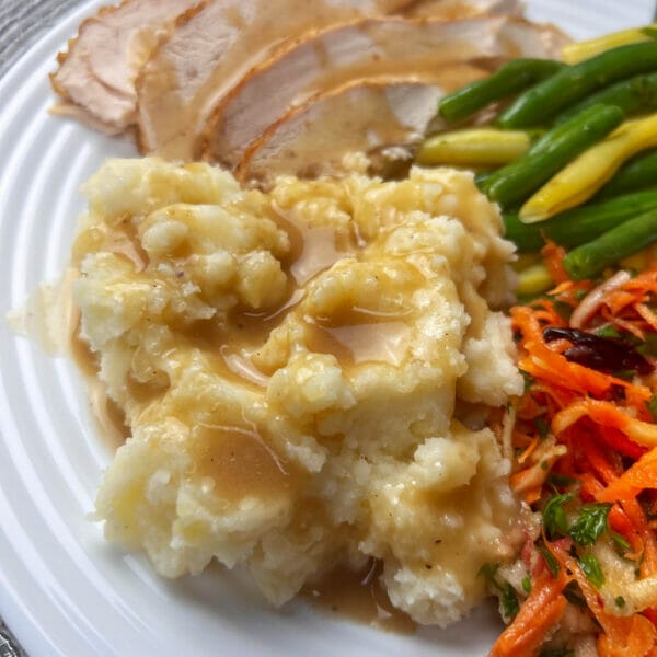 gravy on mashed potatoes and other food on plate