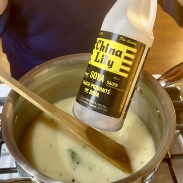 soy sauce over pot of white gravy