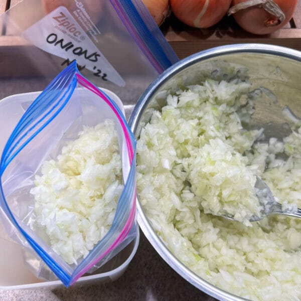 scooping diced onions from bowl into freezer bag