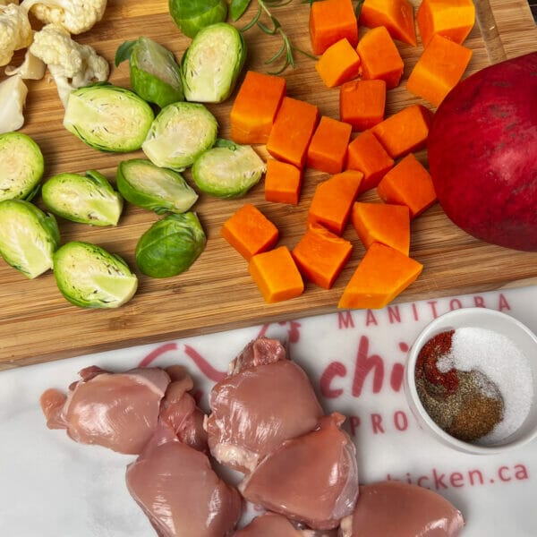 raw veggies, seasoning and chicken on cutting board 
