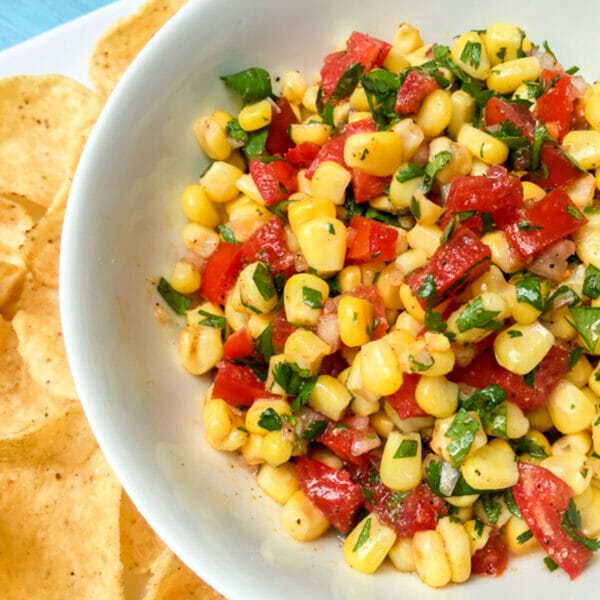 corn niblets, tomatoes and herbs in bowl next to tortilla chips