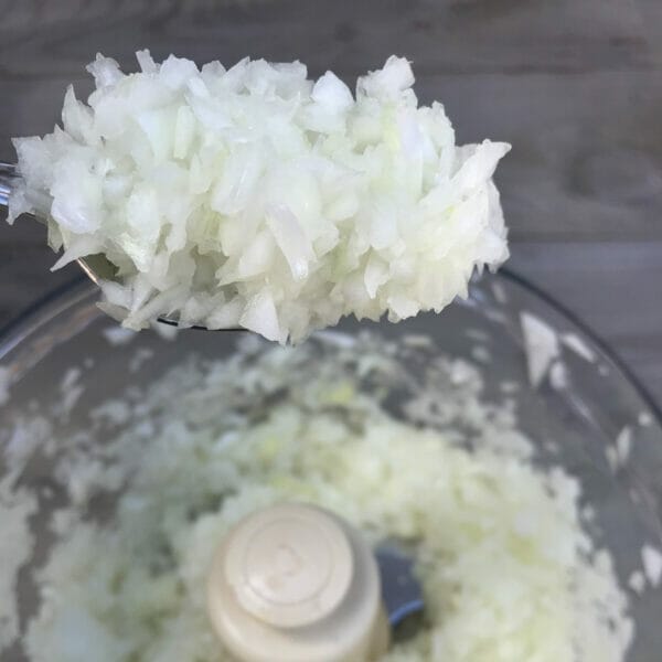 spoon of diced onions hovering over food processor
