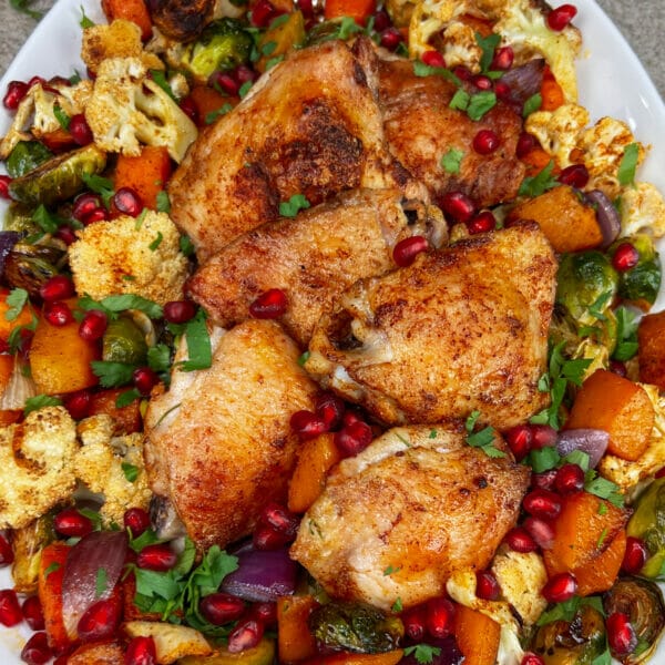 finished broiled chicken on platter with veggies and pomegranates