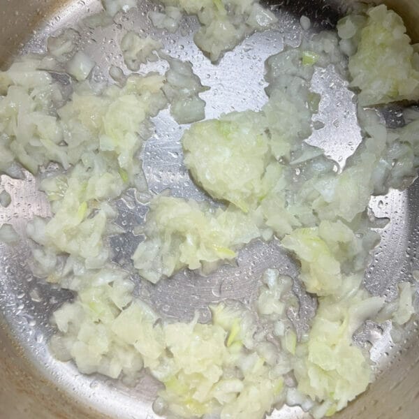 frozen onions being cooked in bottom of pot, drops of moisture visible