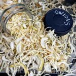 open jar with dried onions resting in dehydrator
