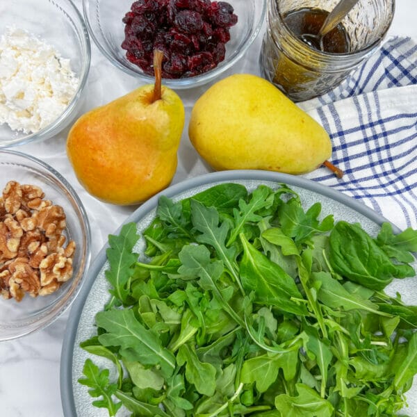 pears and ingredients to dress bowl of arugula
