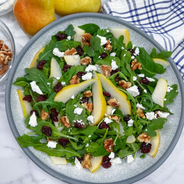 bowl of arugula with pears, feta, walnuts, cranberries not dressed
