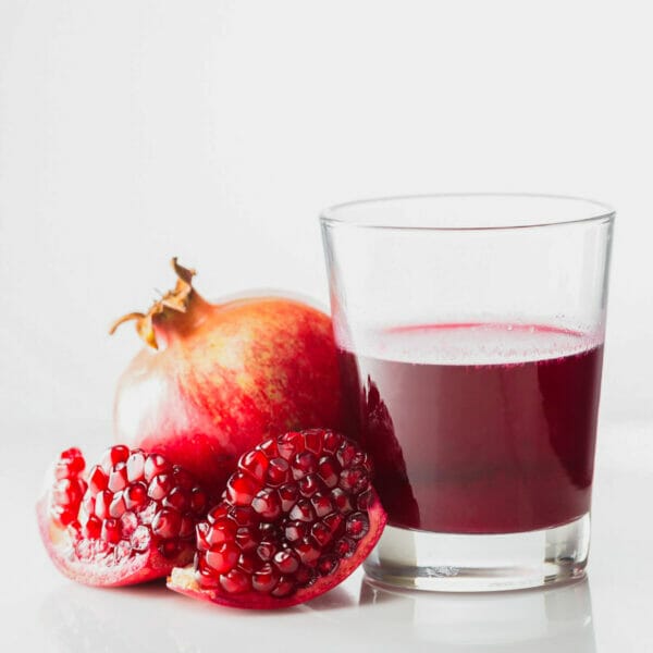 pomegranate with glass half full with ruby red, transparent juice