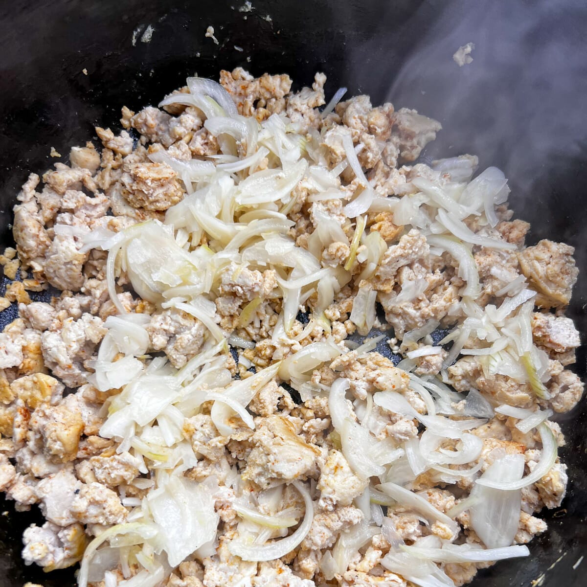 browned ground chicken in pot with rehydrated onions on top