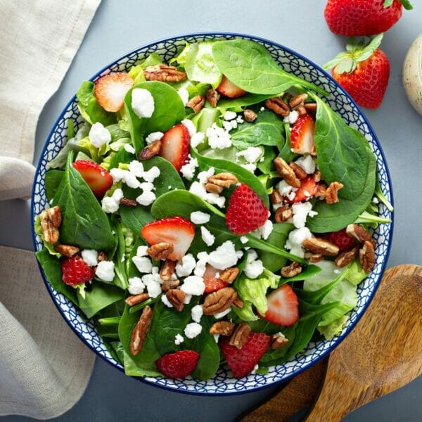 strawberries, goat cheese and pecans on spinach in big bowl