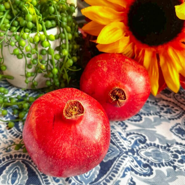 two whole pomegranates on blue and white table cloth