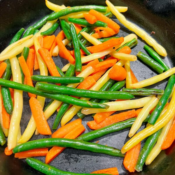 whole green and yellow beans with carrots in dry cast iron pan